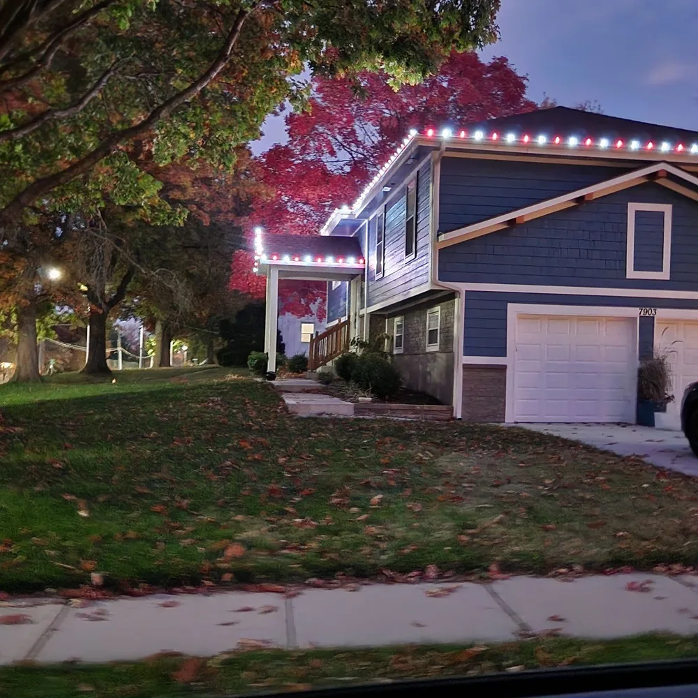Warm white and red C9 bulbs on a two-story stone and stucco home at dusk