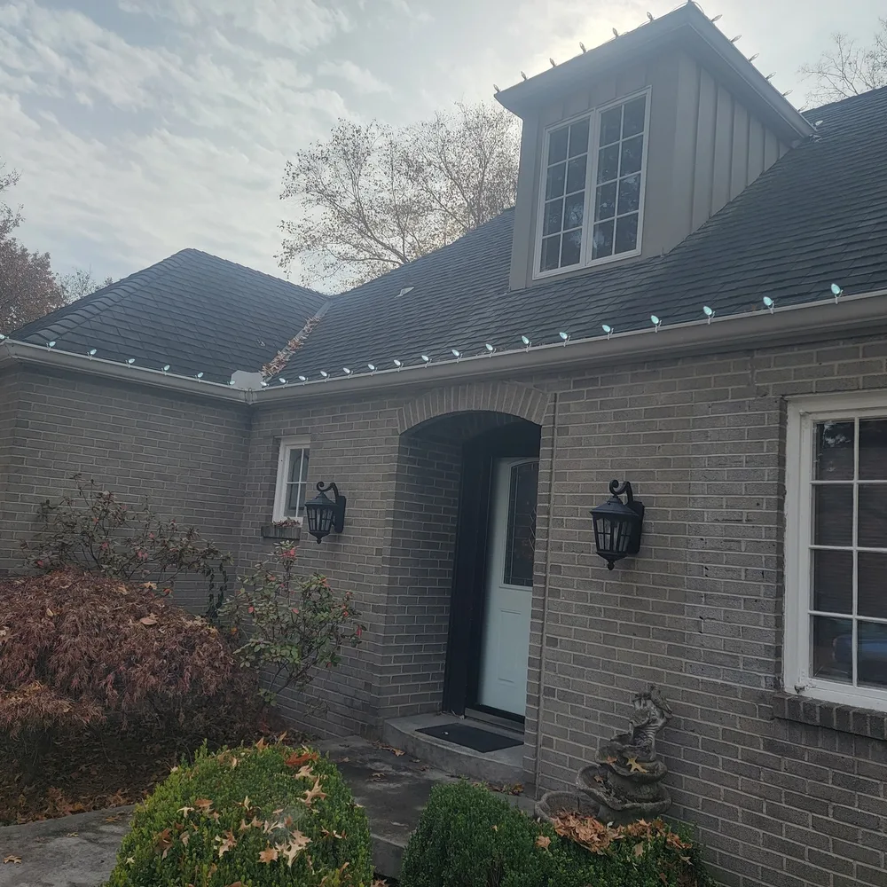 Warm white C9 bulbs along the roofline of a blue two-story home