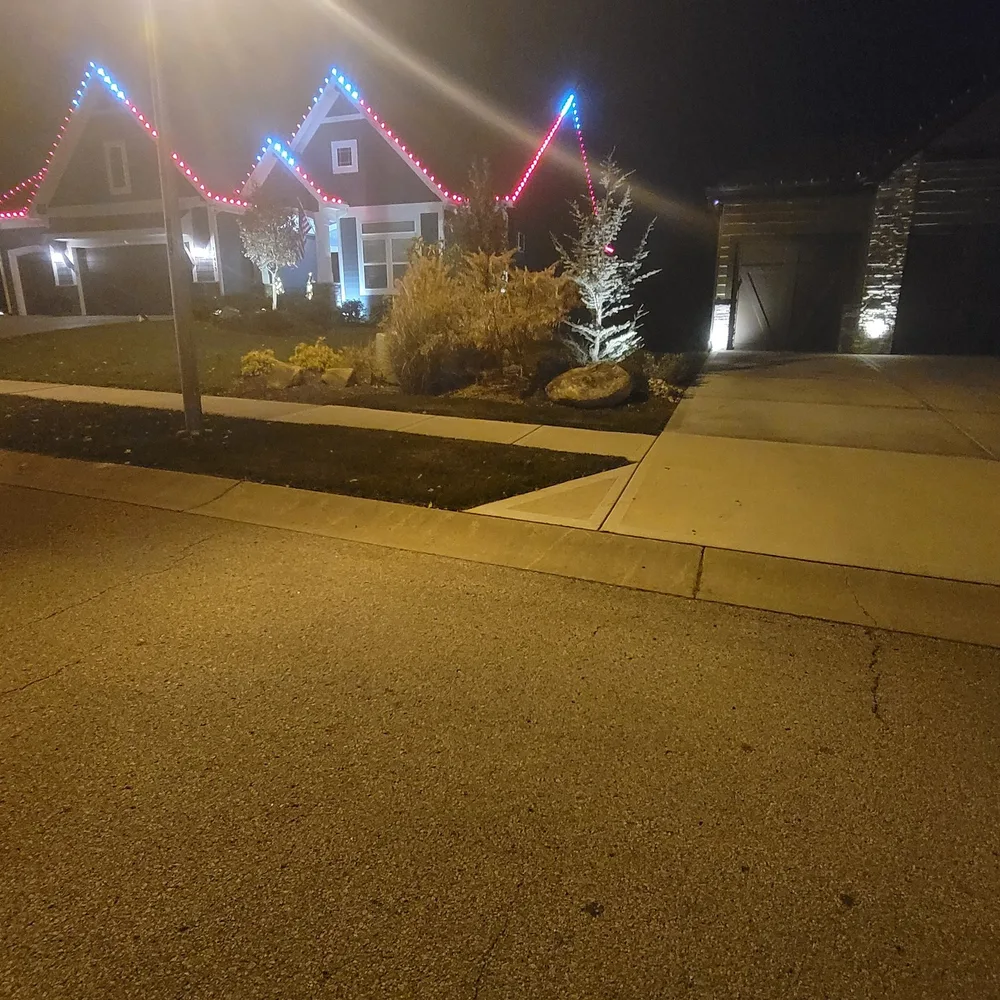 Red and white C9 bulbs along the roofline and porch railing of a ranch home