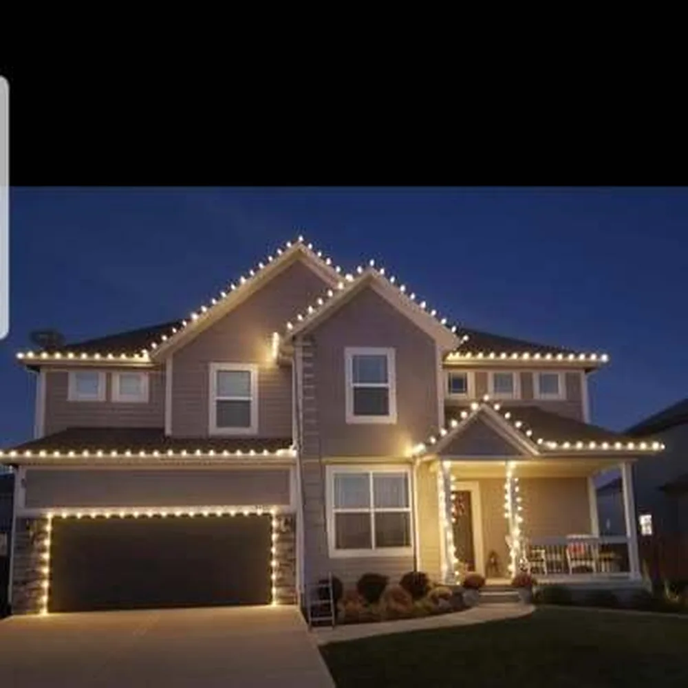 Warm white C9 bulbs on a tan two-story home with an extension ladder and truck in the driveway