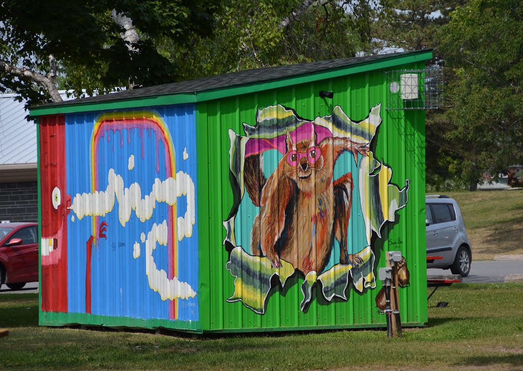 Hand-painted mural of a squirrel wearing heart-shaped glasses bursting through a green shipping container at Pop-Ups on the Bay.