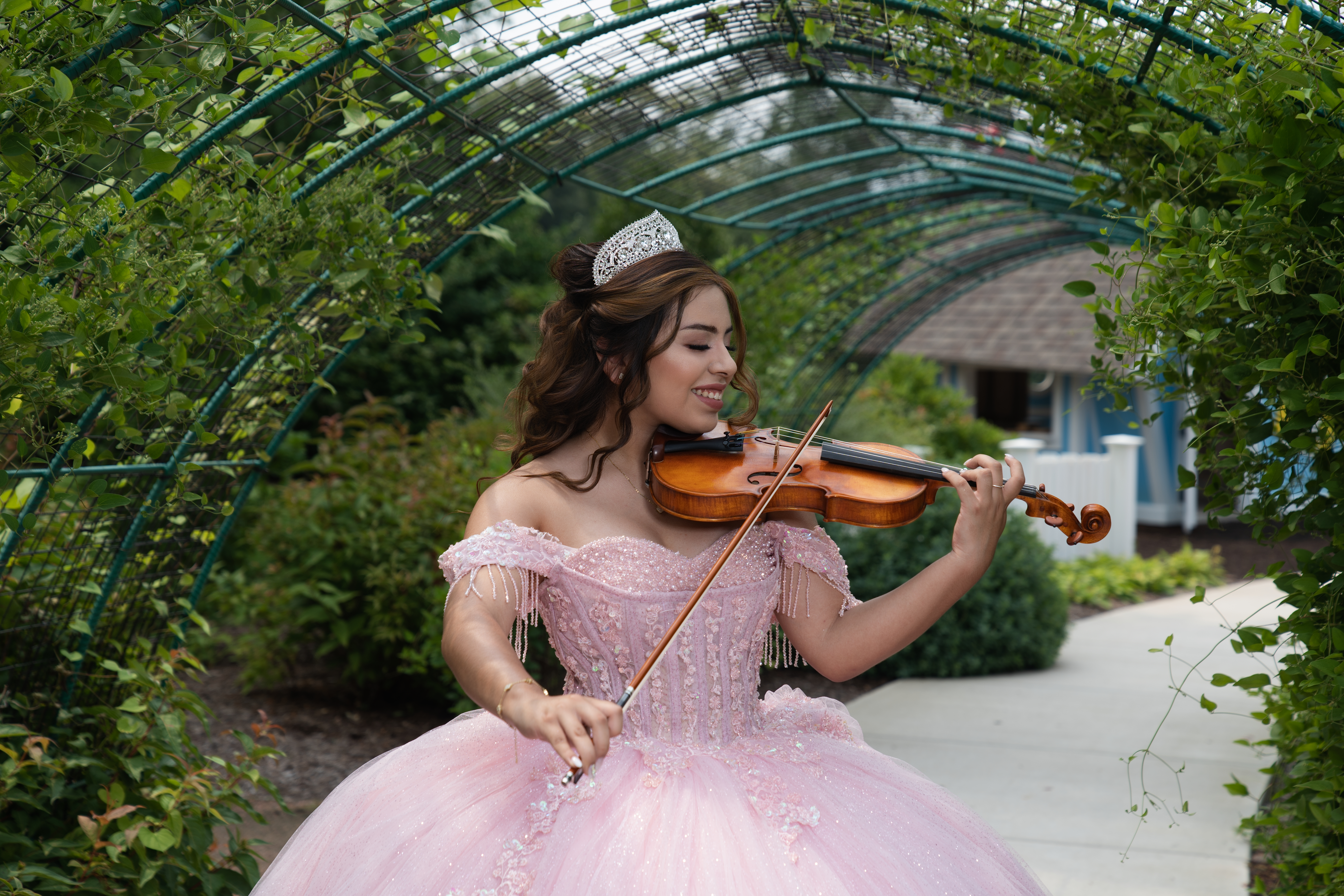 Quinceañera tocando violín en un jardín