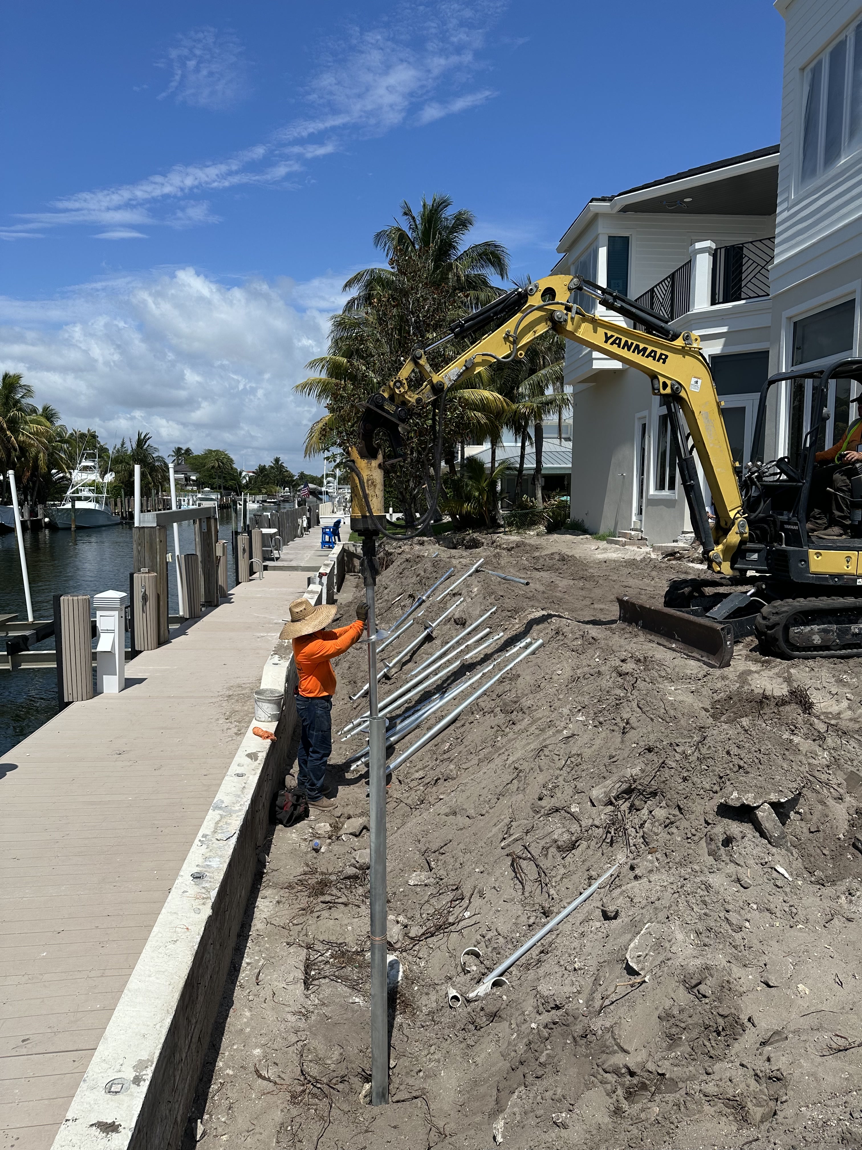 SCFS crew member guiding a steel pile beside compact installation equipment on a waterfront site