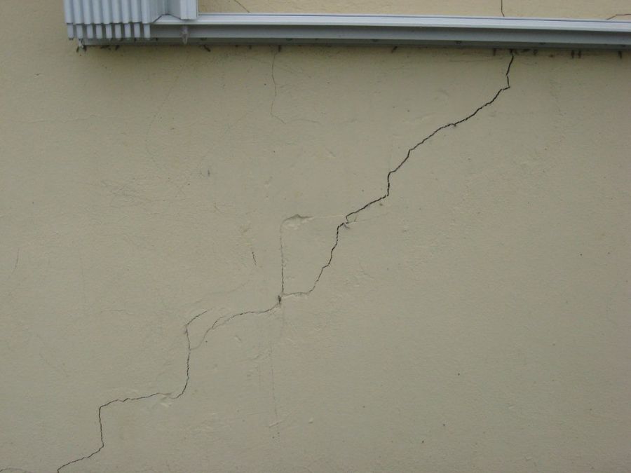 Stair-step crack running diagonally across a stucco wall