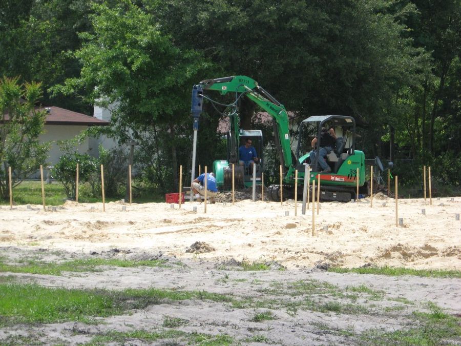 Pile locations staked out on an open lot with a pile-driving rig