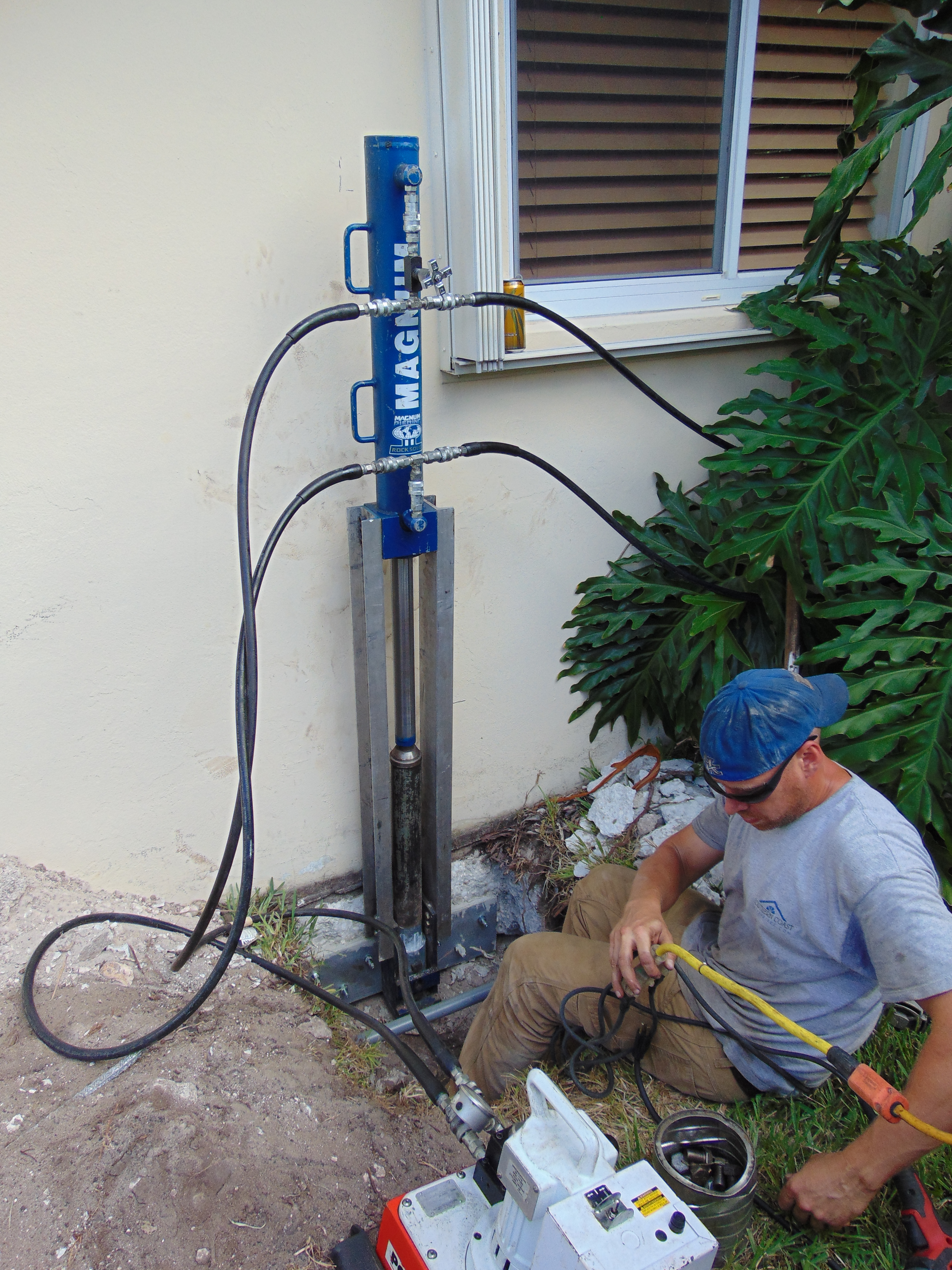 SCFS employee working beside foundation stabilization equipment at a South Florida home