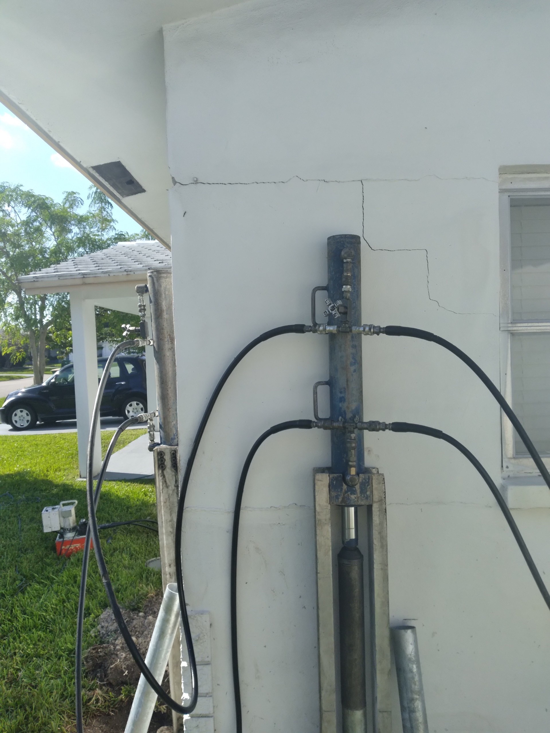 The same wall area during foundation repair with the visible crack narrowed and stabilization equipment still in place