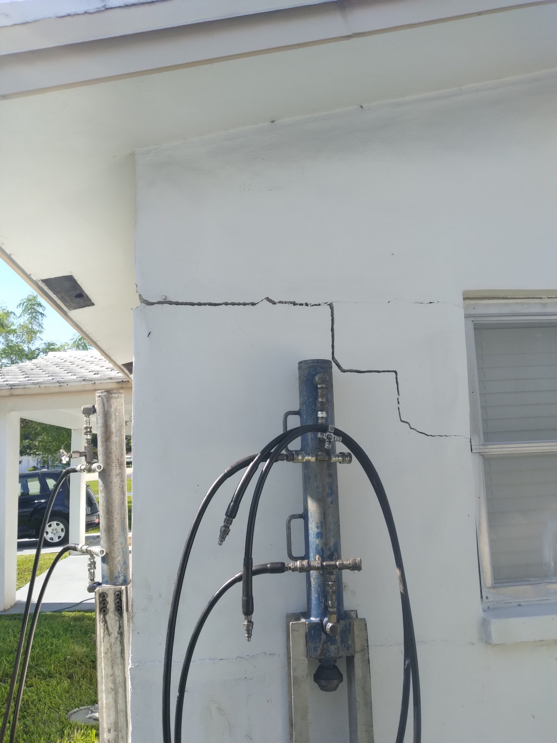 Pronounced stepped wall crack with foundation stabilization equipment in place before controlled correction