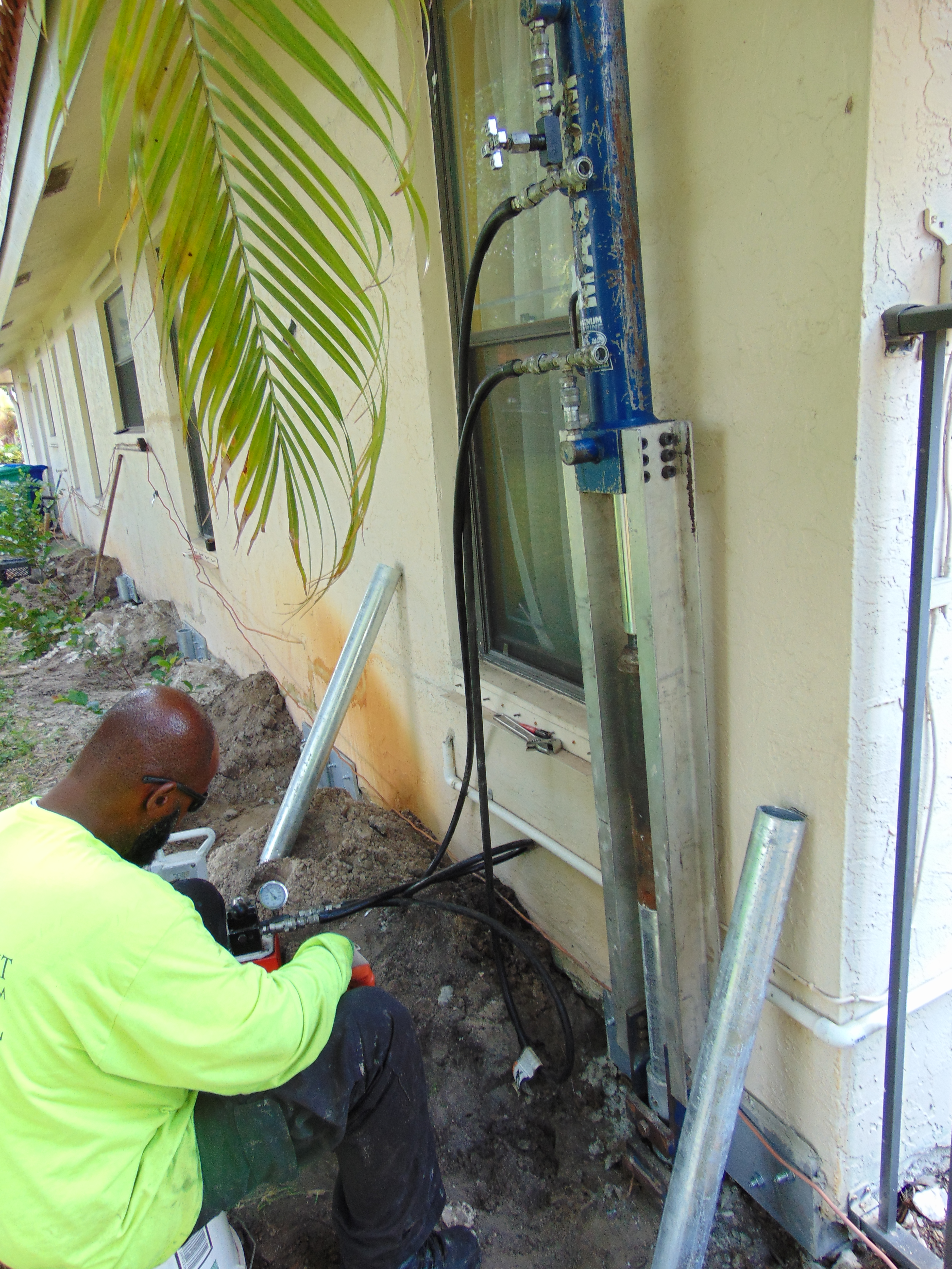 Southern Coast Foundation Systems crew member working at a foundation pier installed along a home's exterior wall