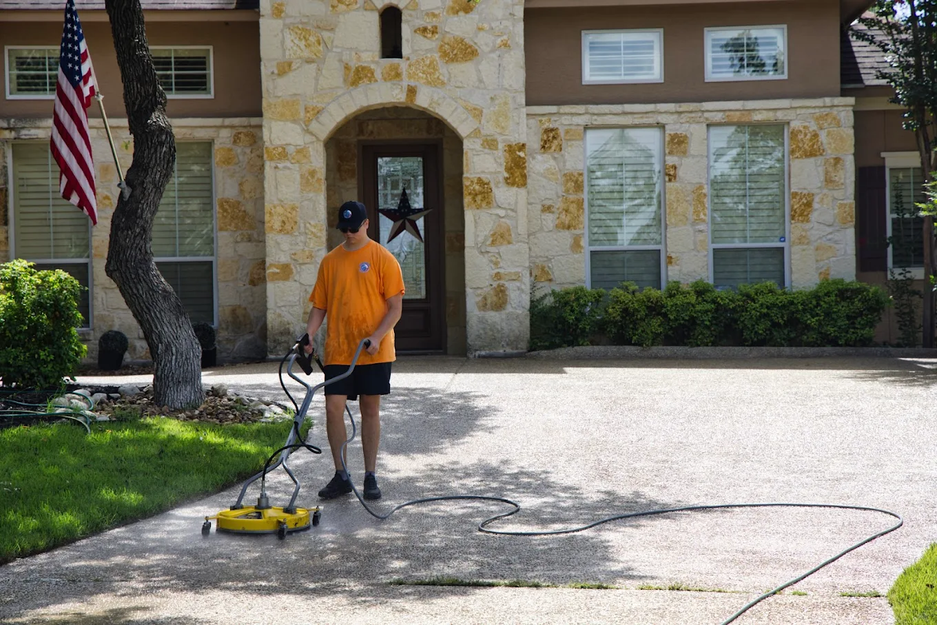 Pressure washing driveway in front of a home to remove dirt, stains, and buildup for improved curb appeal.