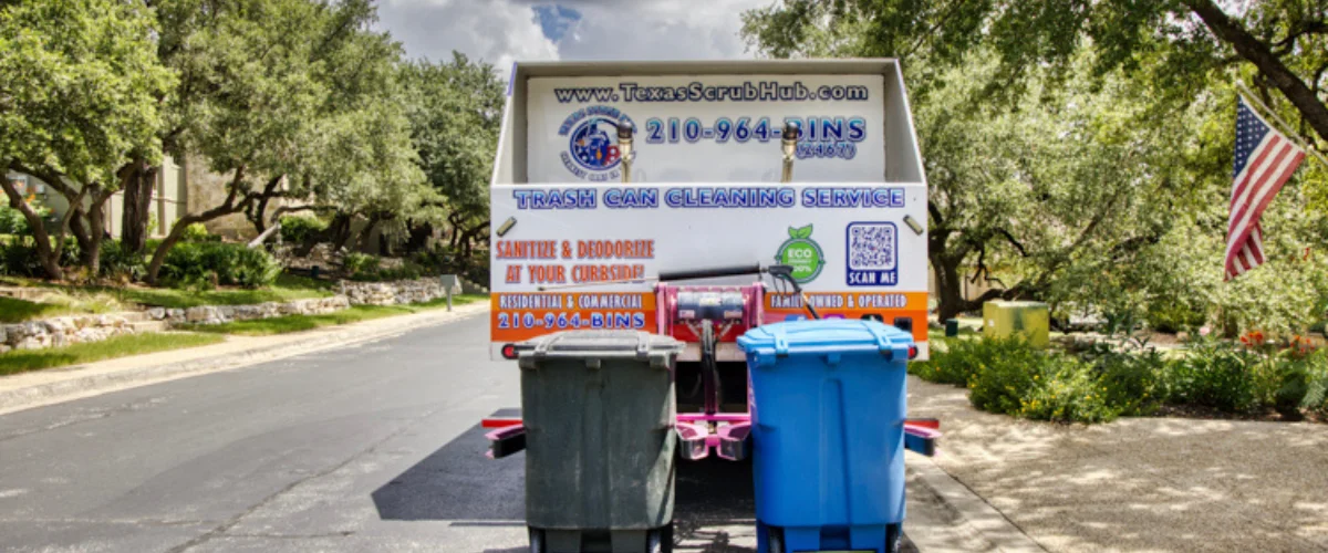 Rear view of a white trash can cleaning service truck with 'Texas ScrubHub' branding, cleaning two trash cans on a suburban street.