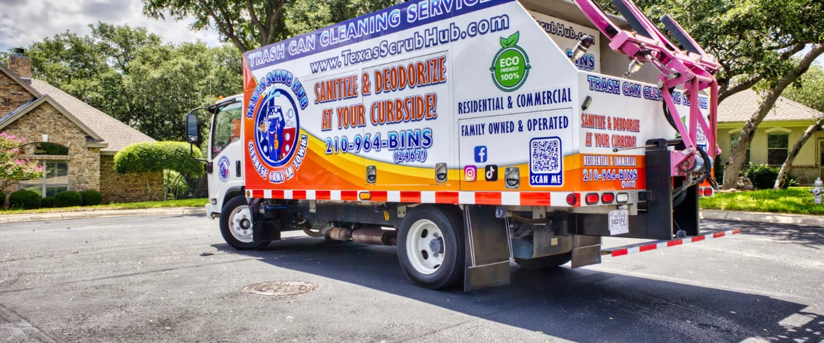 A white and orange Texas Scrub Hub trash can cleaning truck parked on a residential street in front of a house.