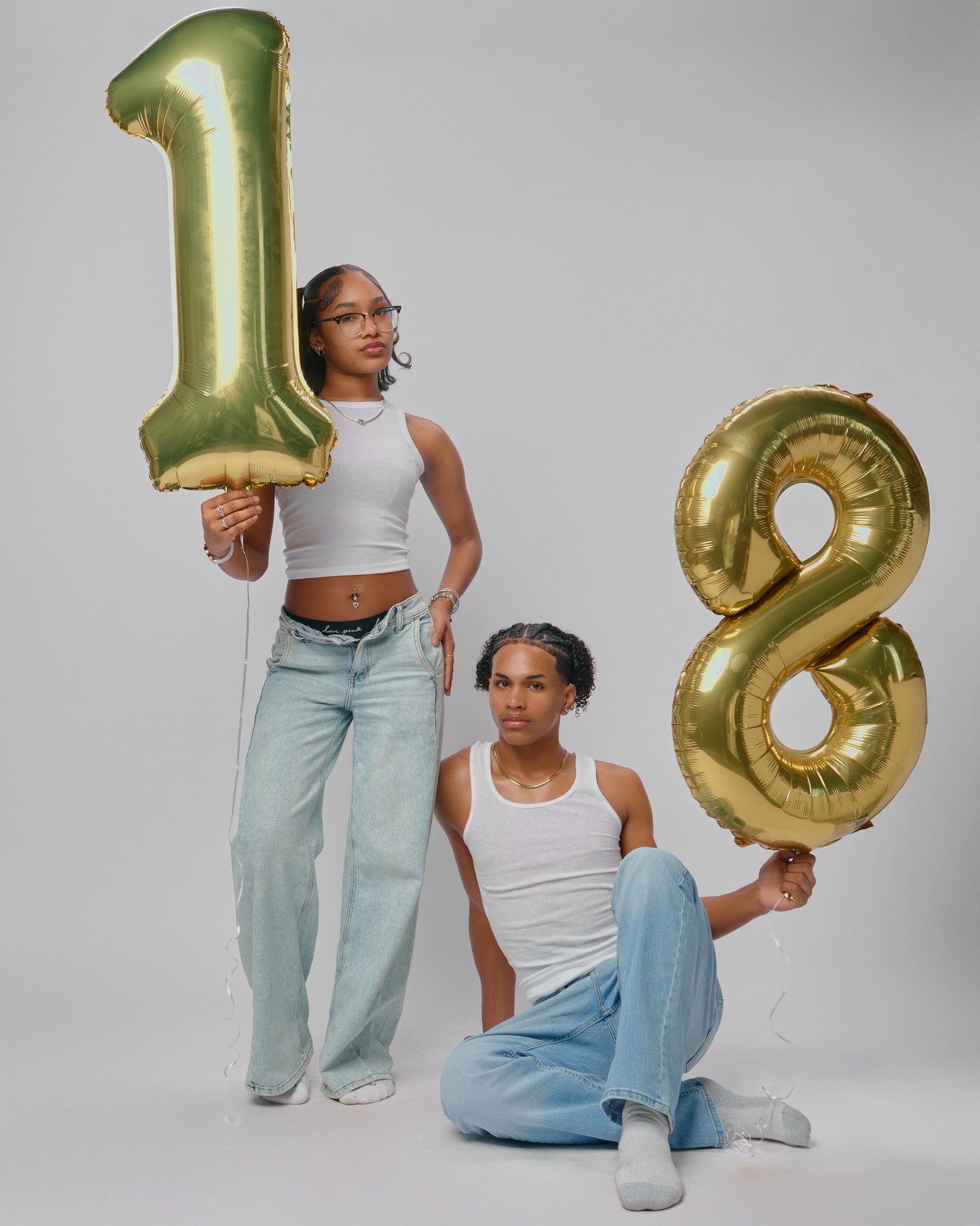 photo of a young man and woman holding the numbers one and eight birthday ballons