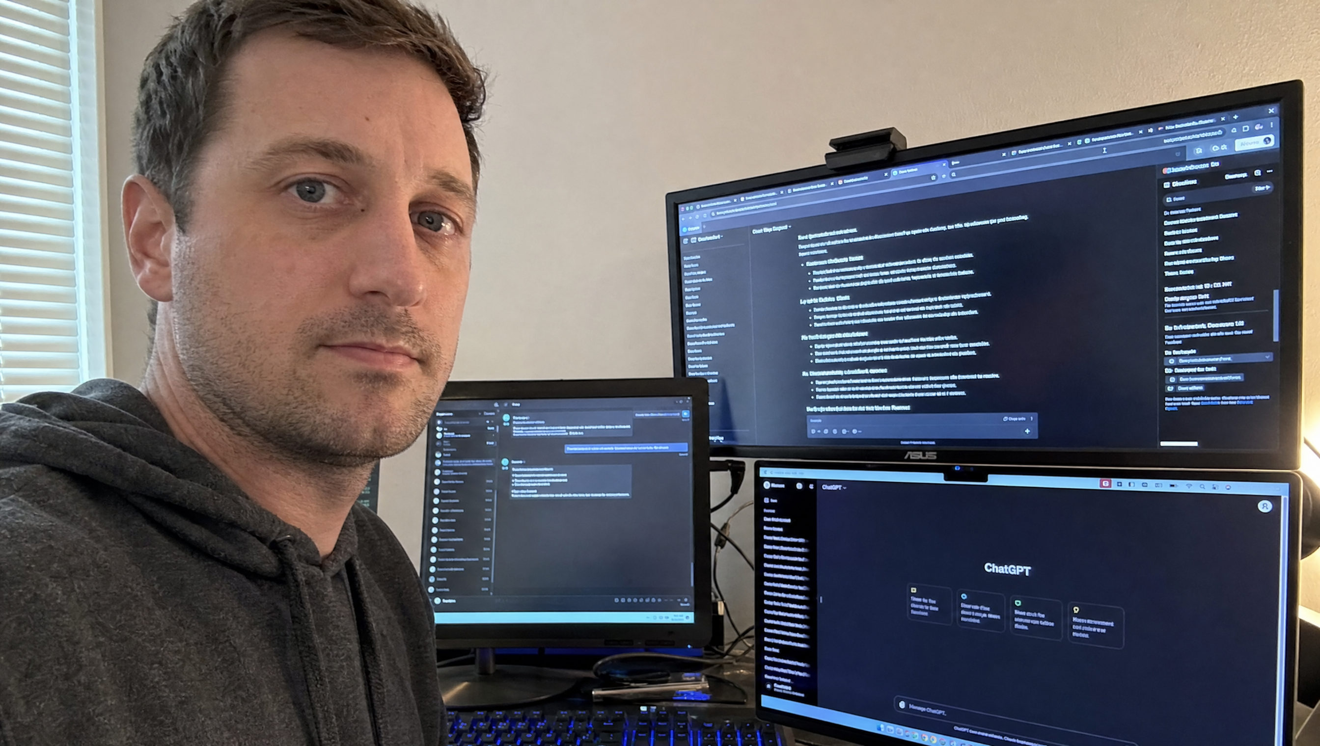 Guy at a triple-monitor desk using ChatGPT and other AI tools for freelance work