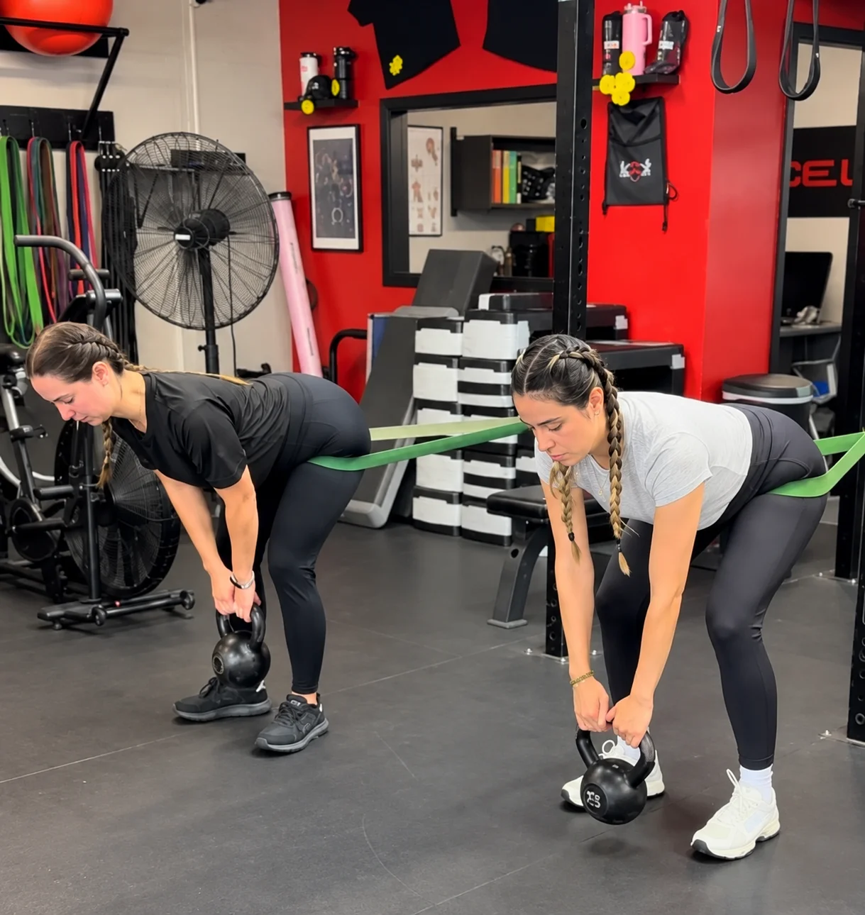 Two women training with kettlebells at Xcel Fitness