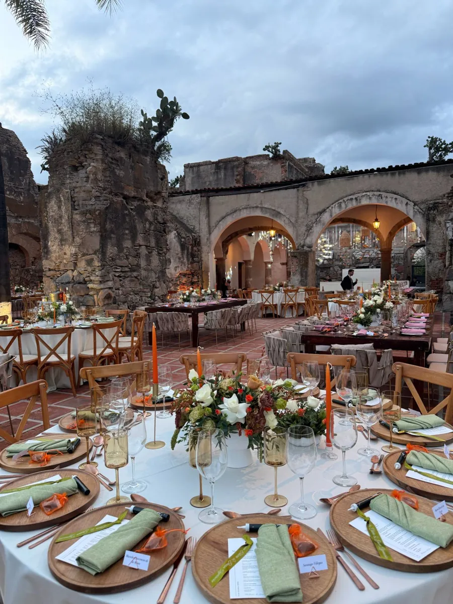 A table set with sage green napkins, wooden chargers and terracotta candles