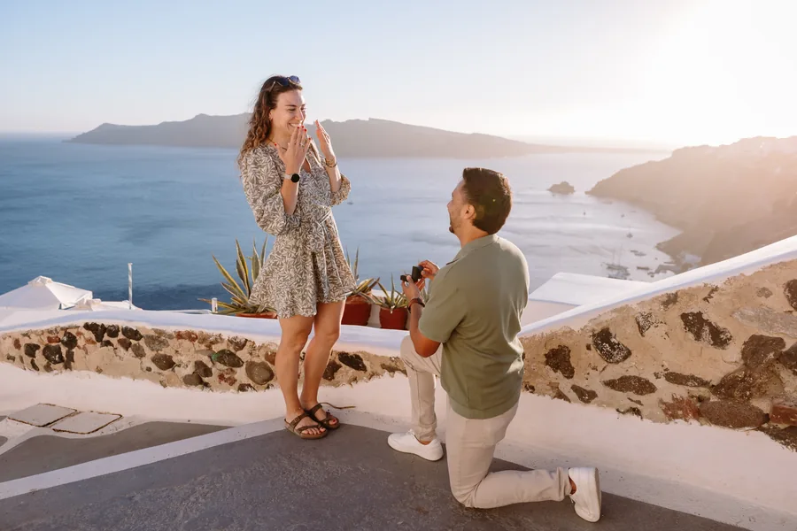 Elise looks down at Ricardo kneeling, the caldera behind her