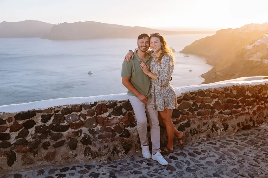 Elise and Ricardo against a stone wall, the sun low behind them