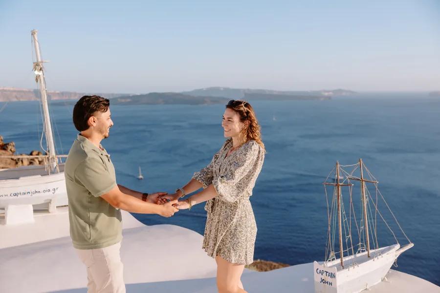 Elise and Ricardo face each other holding hands, the bay behind them