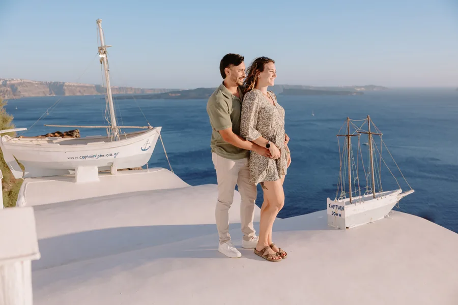 The two of them by the boat, holding each other, the island across the water