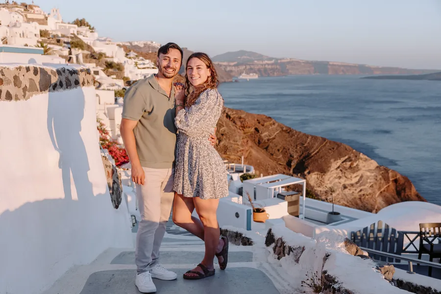 Elise and Ricardo on the white steps of Oia, red cliffs and bougainvillea behind