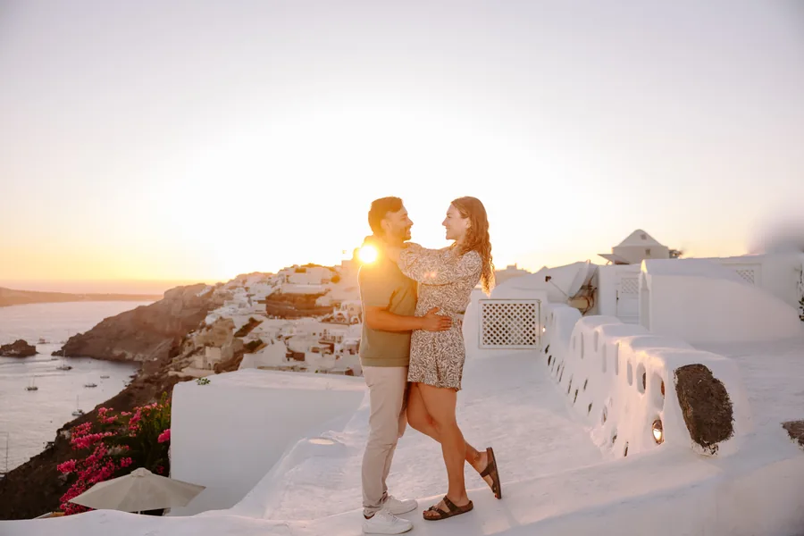 Elise and Ricardo wrapped in the sunset above Oia, bougainvillea in the corner