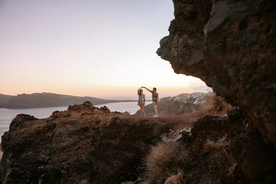 Under the rock arch on the cliff, Ricardo spinning Elise, the sky going pink