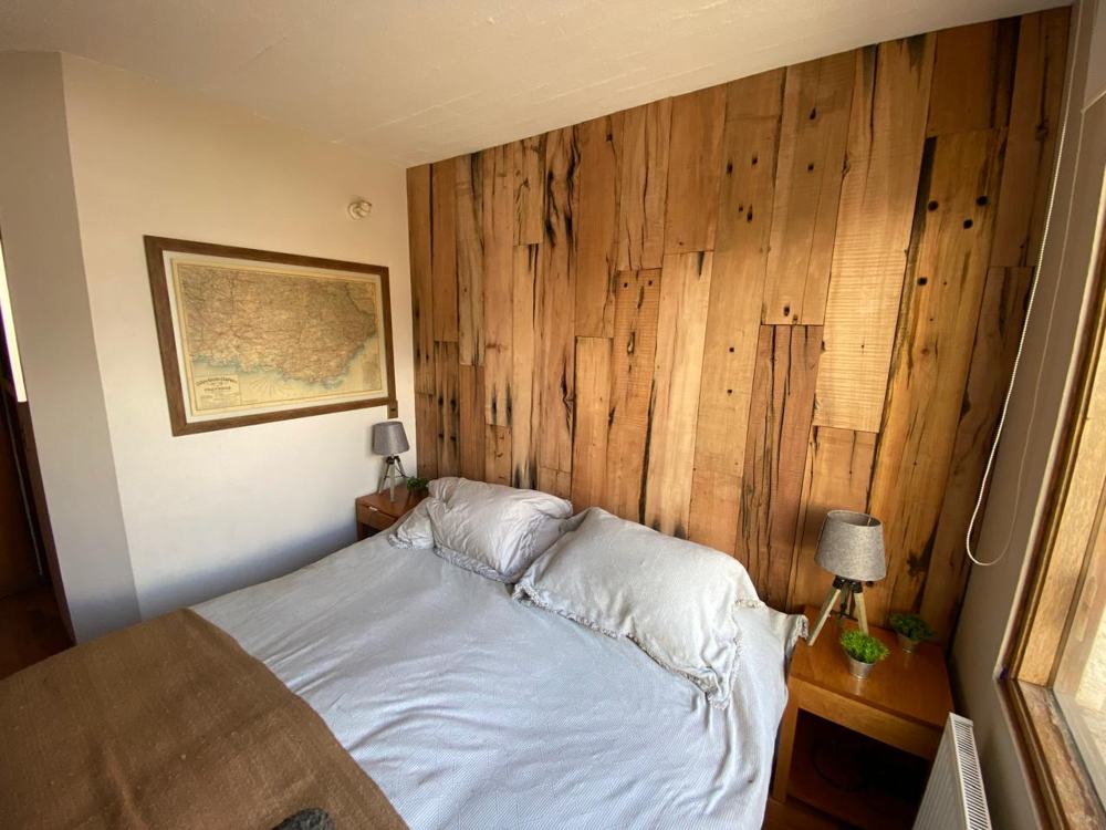 Dormitorio en La Parva con muro de respaldo revestido en durmientes de madera