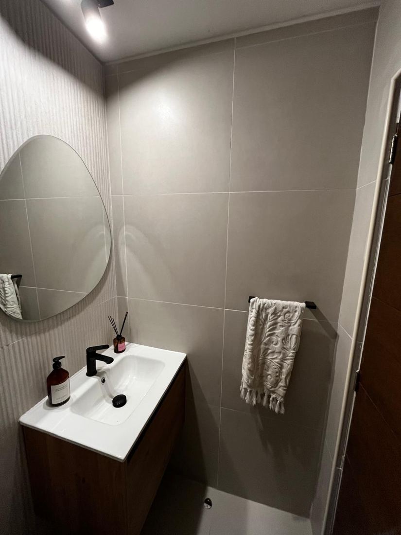 Baño de visitas con porcelanato de gran formato y mueble de madera