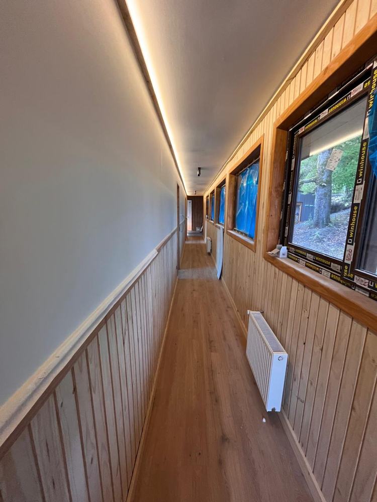 Pasillo con friso de madera, iluminación lineal y calefacción