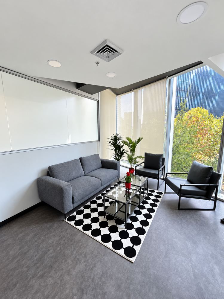 Sala de espera de la oficina con sofá, sillones y ventanales