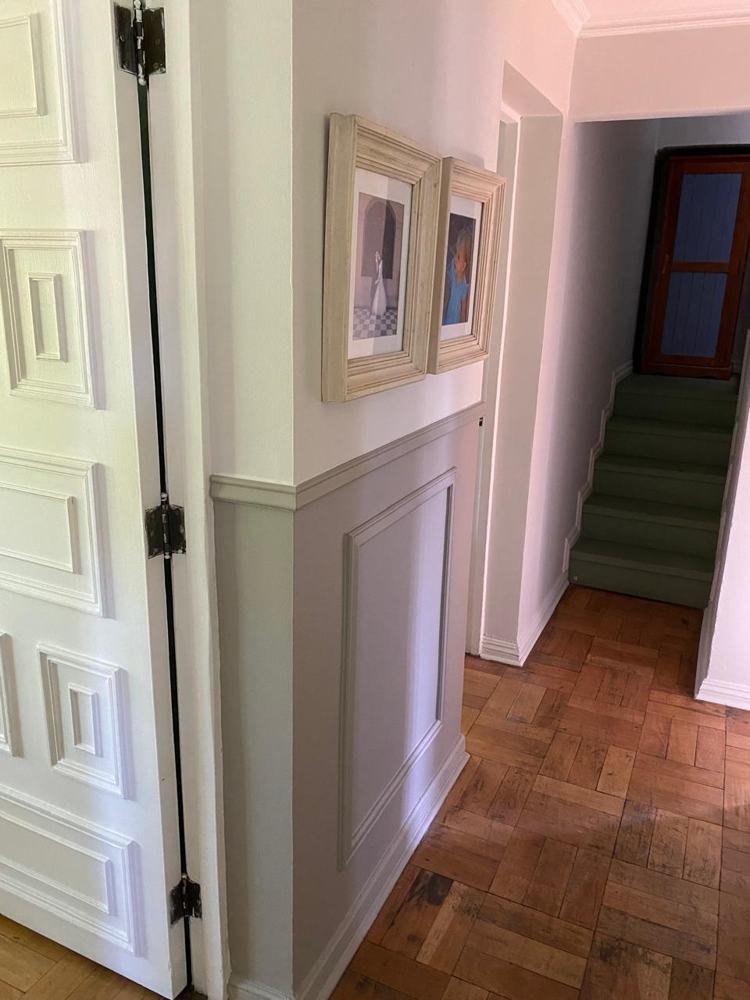 Pasillo con zócalo de molduras pintado y piso de parquet