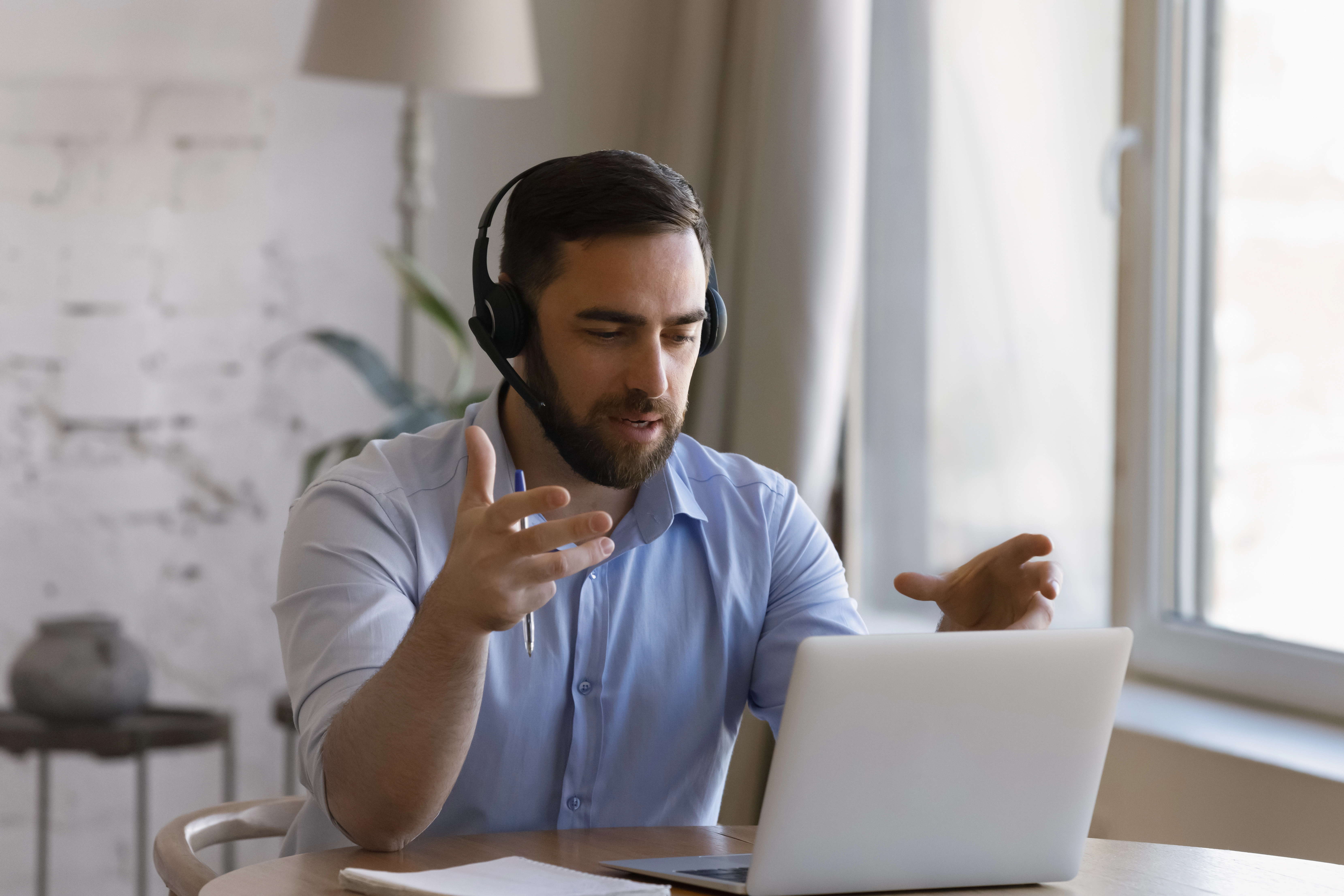 business man wearing headphones on a virtual meeting on laptop