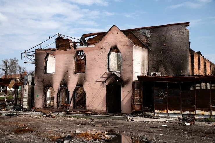 A two-story pink building with a collapsed roof and blackened facade from extensive fire damage and destruction.