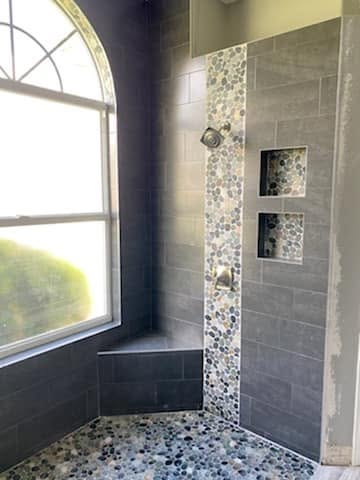 Dark shower with pebble accent and bench