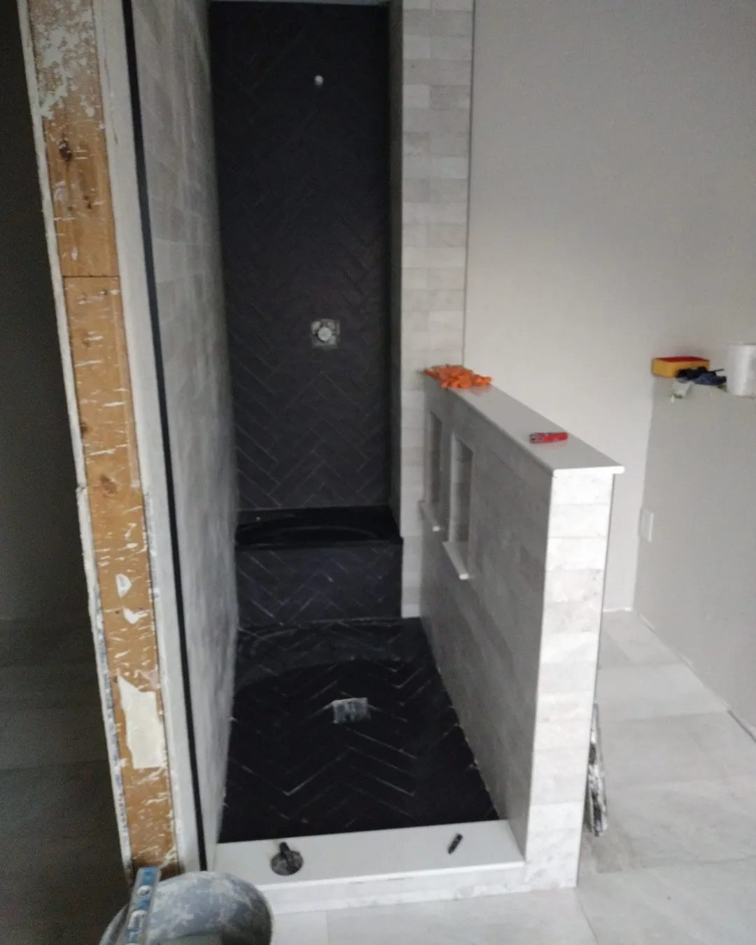 Walk-in shower with herringbone floor and niches under construction
