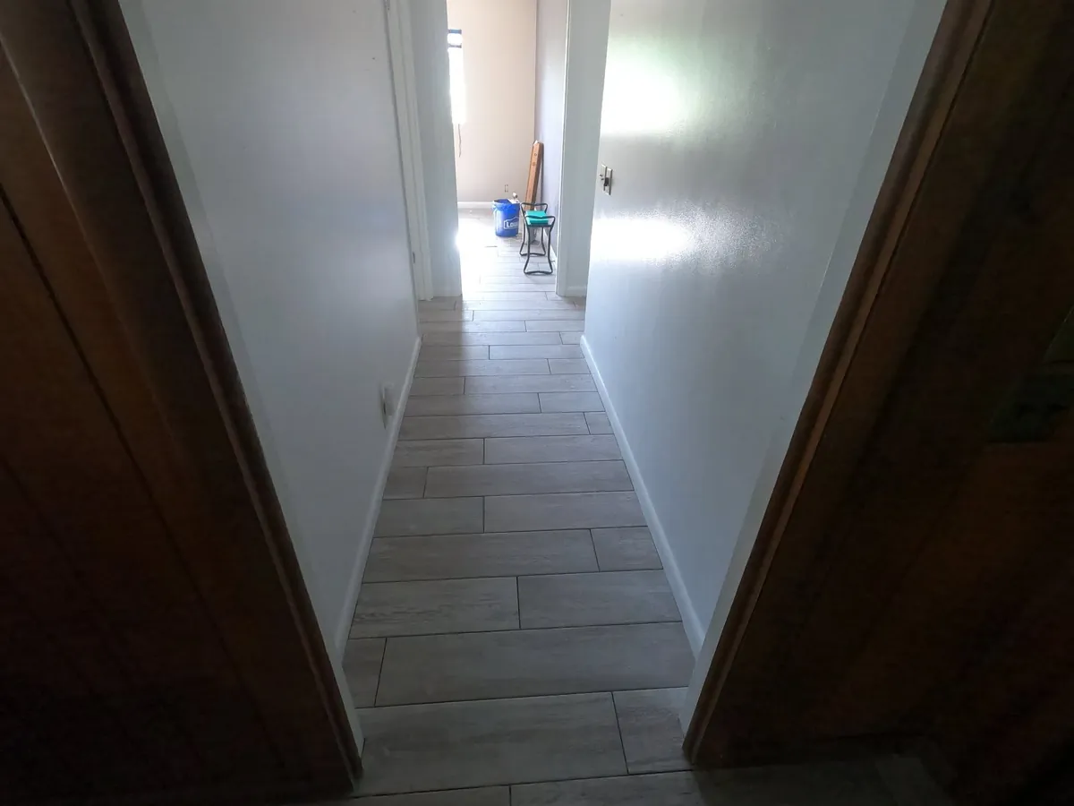 Wood-look hallway toward lit room