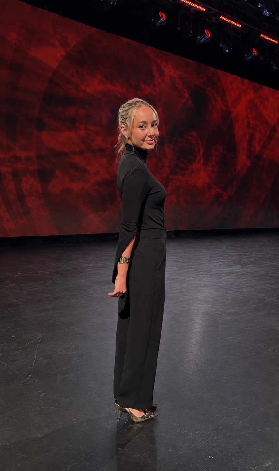 Client wearing an all-black tailored look on stage