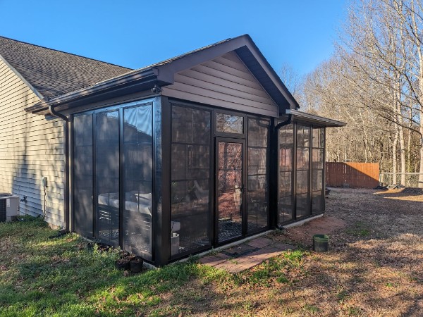 Exterior dark-framed porch enclosure connected to a home