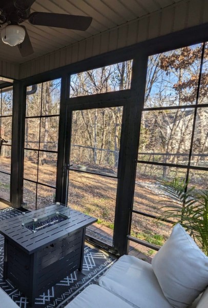 Dark-framed porch enclosure overlooking a wooded backyard