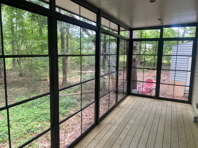 Interior screen porch with dark framing and wooded views