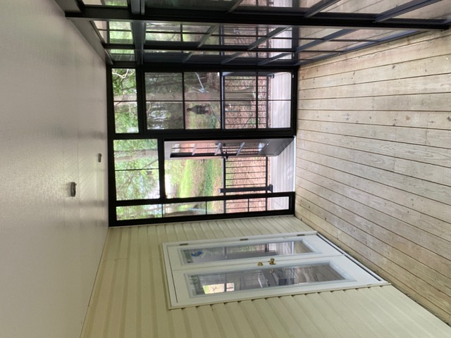 Interior view of an enclosed outdoor room with a ceiling fan and door