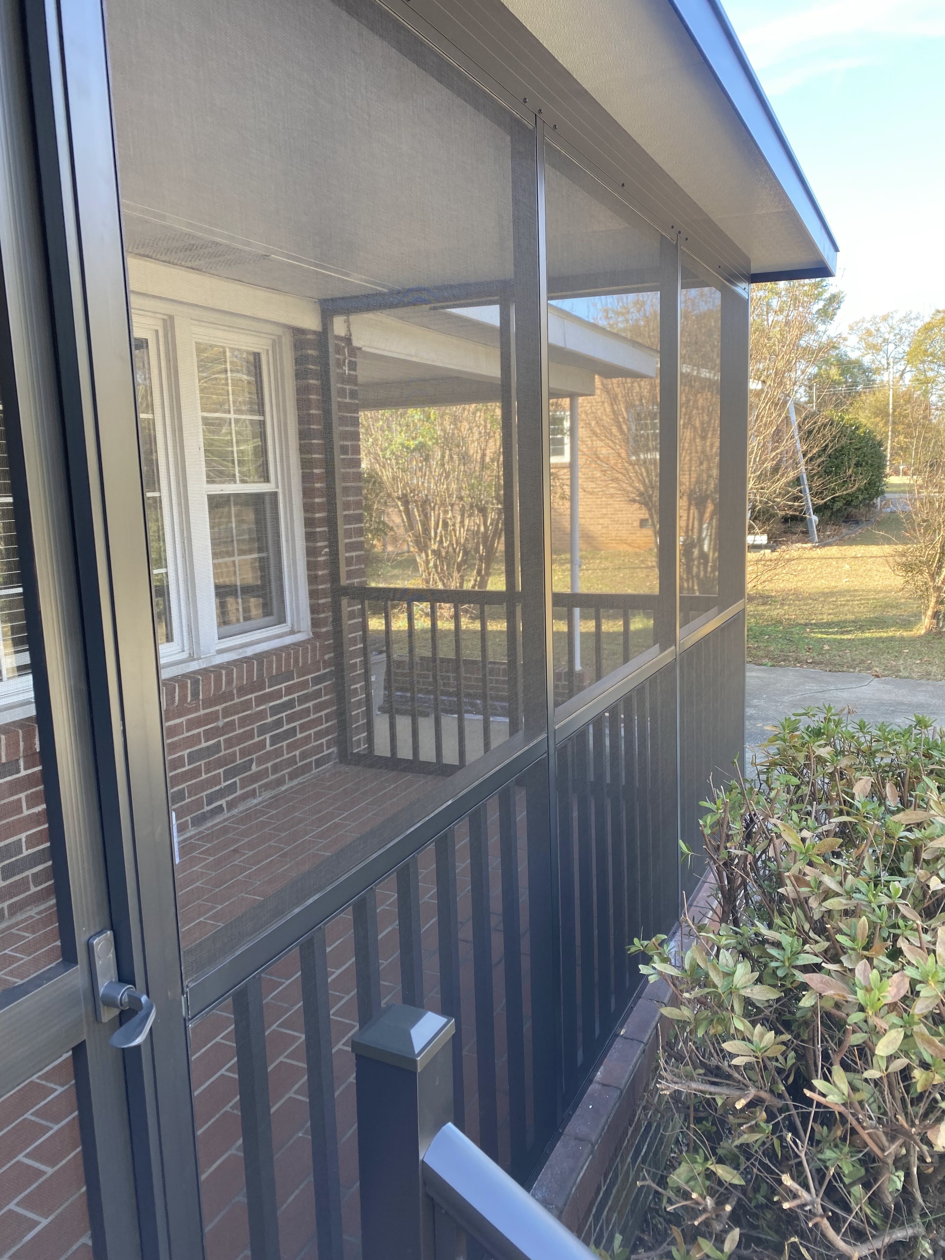 Finished side view of the Rebecca screened porch with dark framing and brick floor