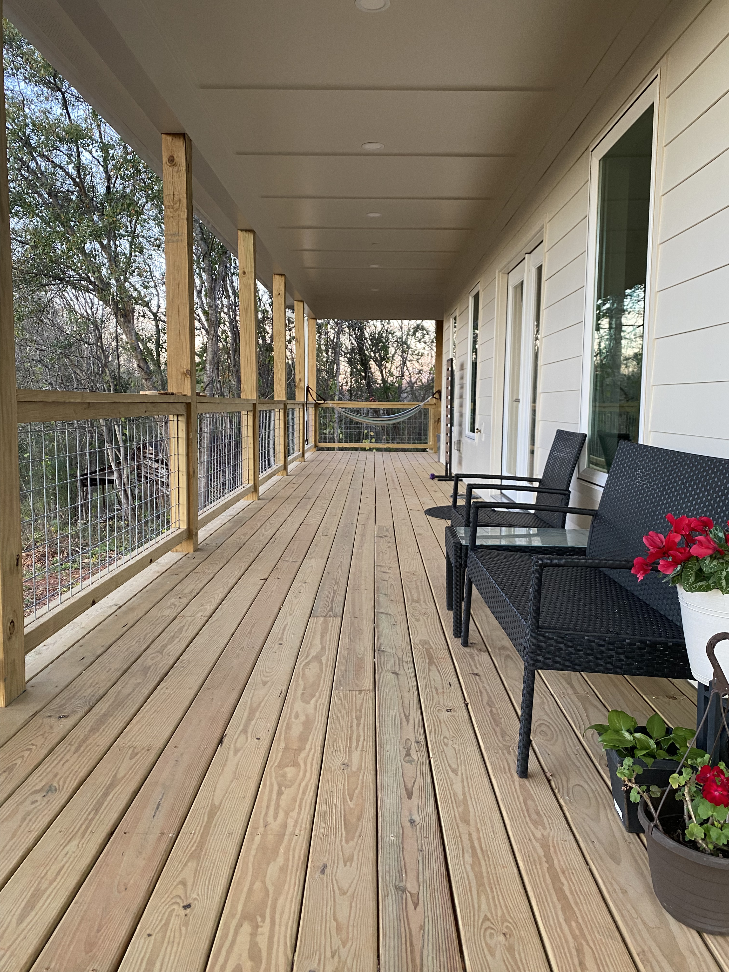 Finished long covered porch with seating and hog-wire railing in the Easley area