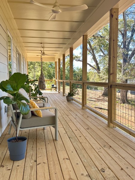 Long furnished Ryan covered porch with seating, plants, ceiling fans, and open railing