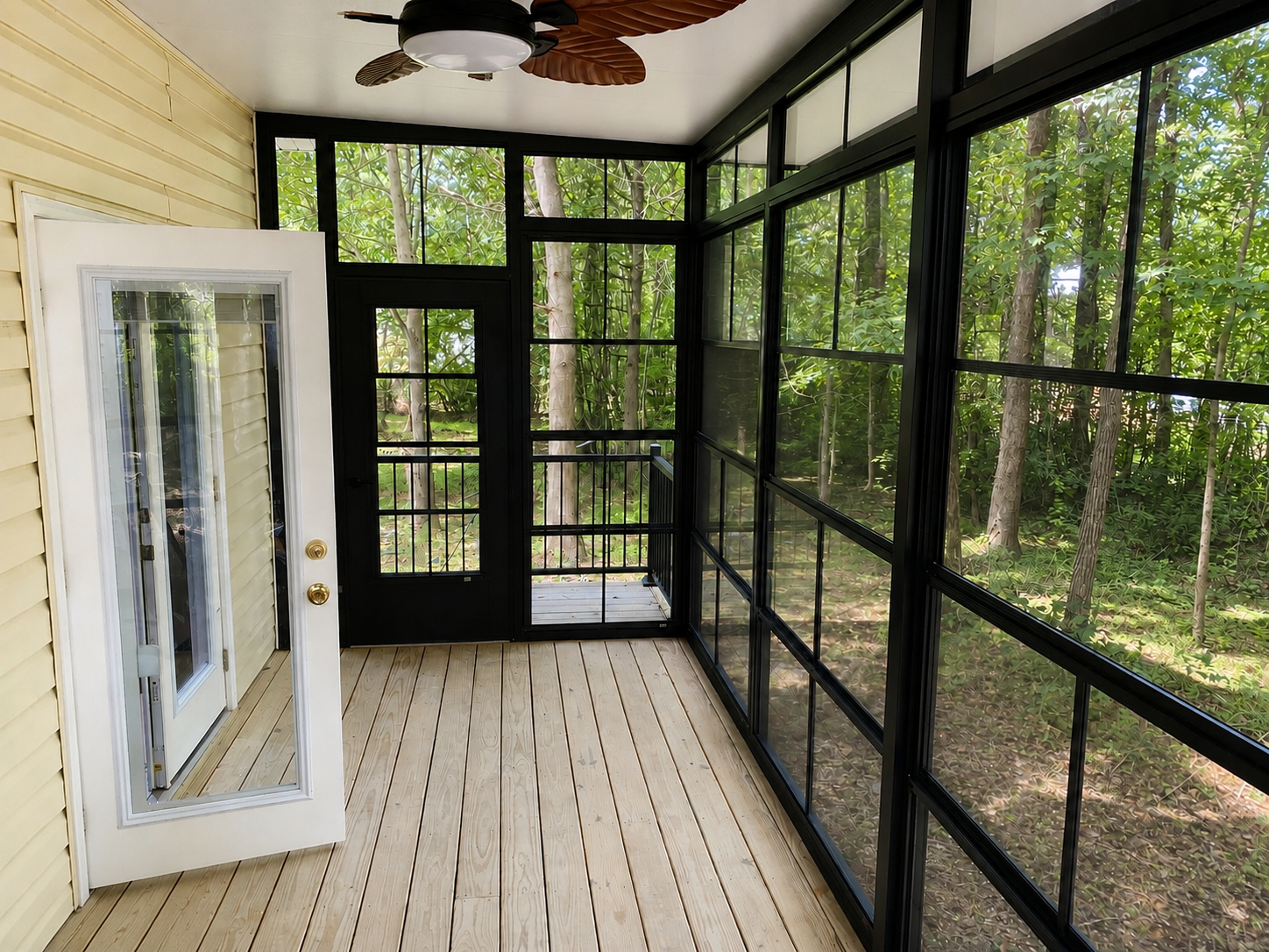 Interior view of the Greenville Eze-Breeze enclosure with ceiling fan, panels, and wooded views