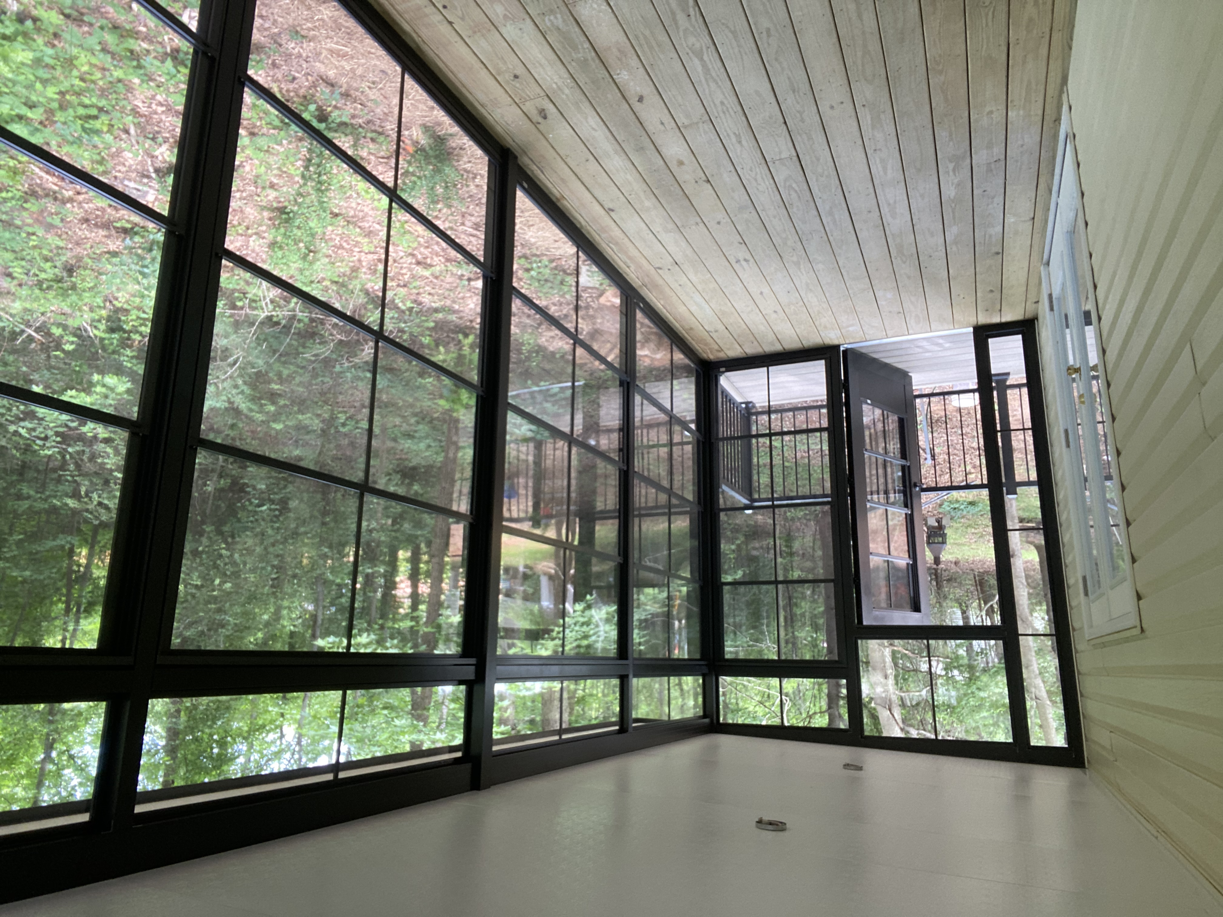 Wide interior view of the finished Greenville Eze-Breeze porch with wood floor and black framing