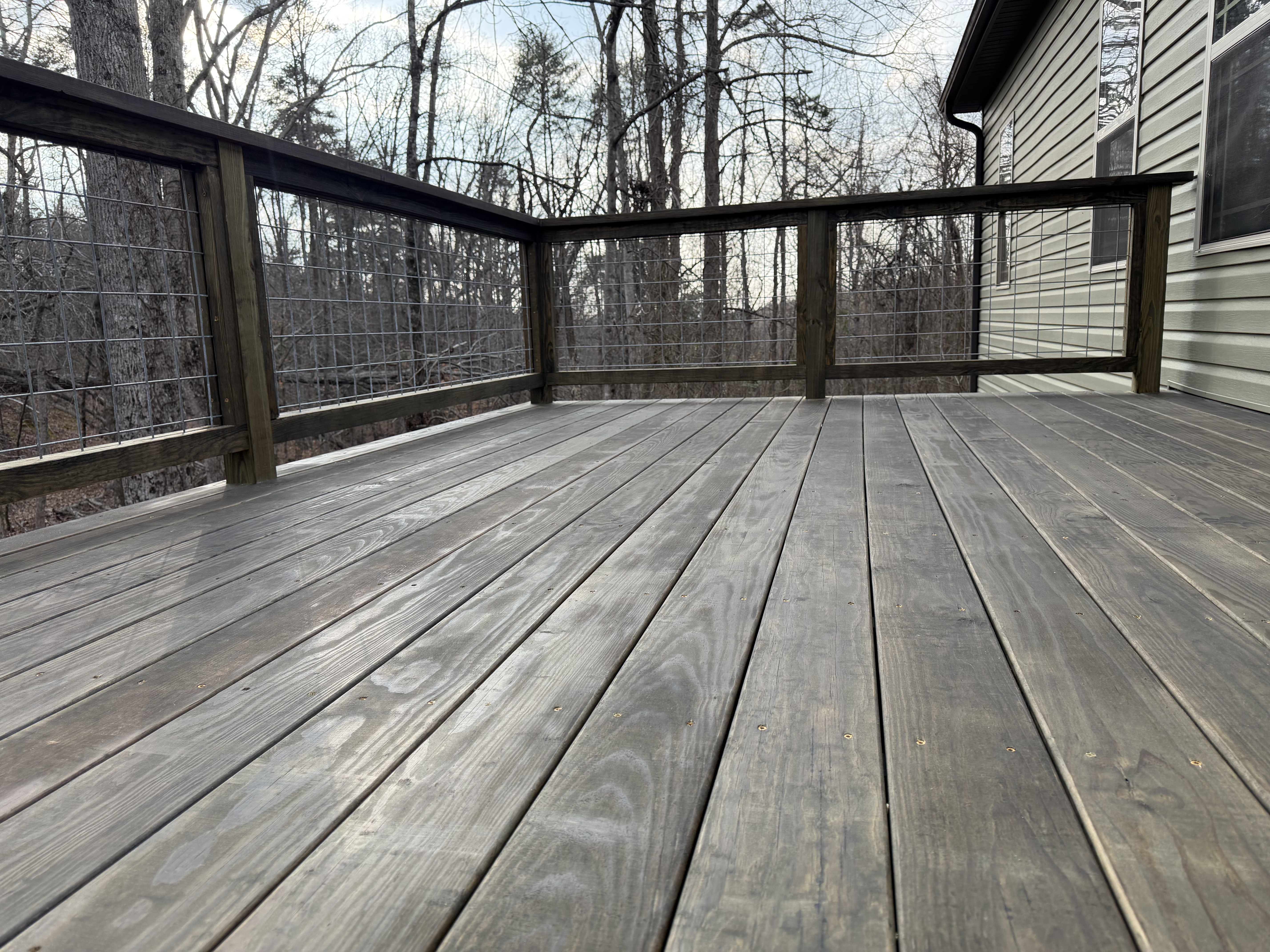 Finished stained wood deck with open hog-wire railing and wooded views in Berea