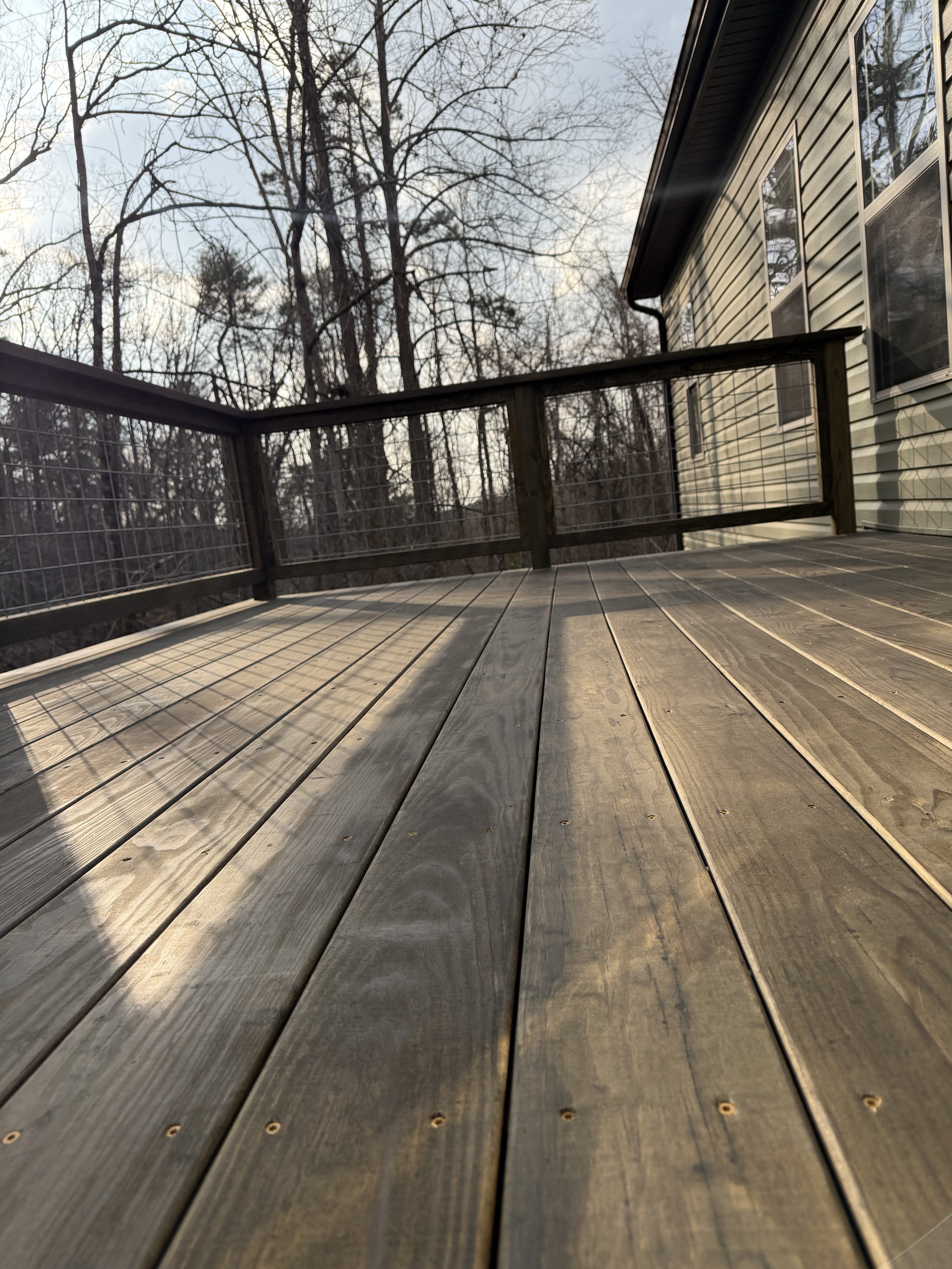 Finished Caleb deck with stained wood surface and hog-wire railing in afternoon light