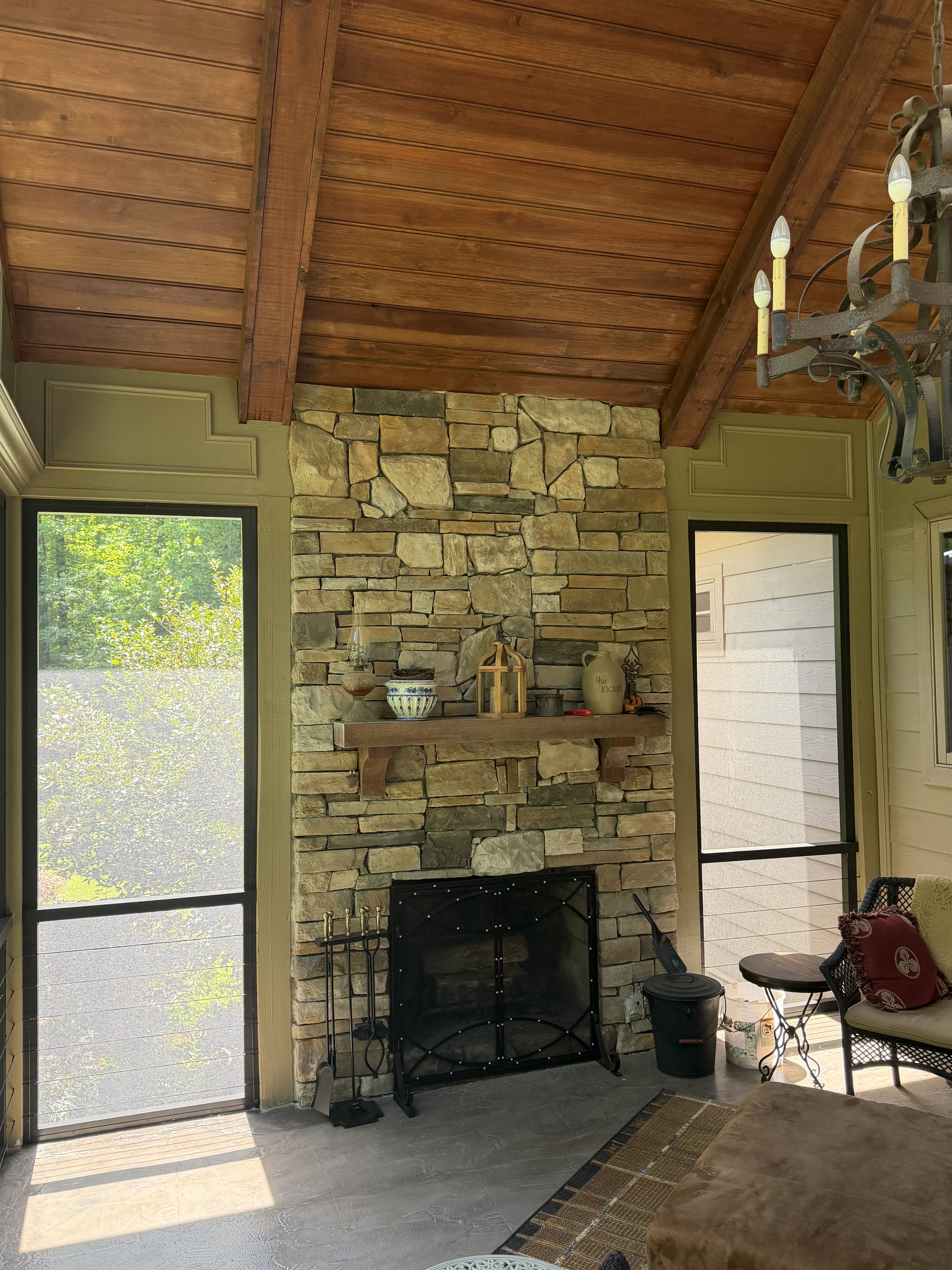 Renovated screen porch with fireplace, wood ceiling, and open screen framing near Paris Mountain